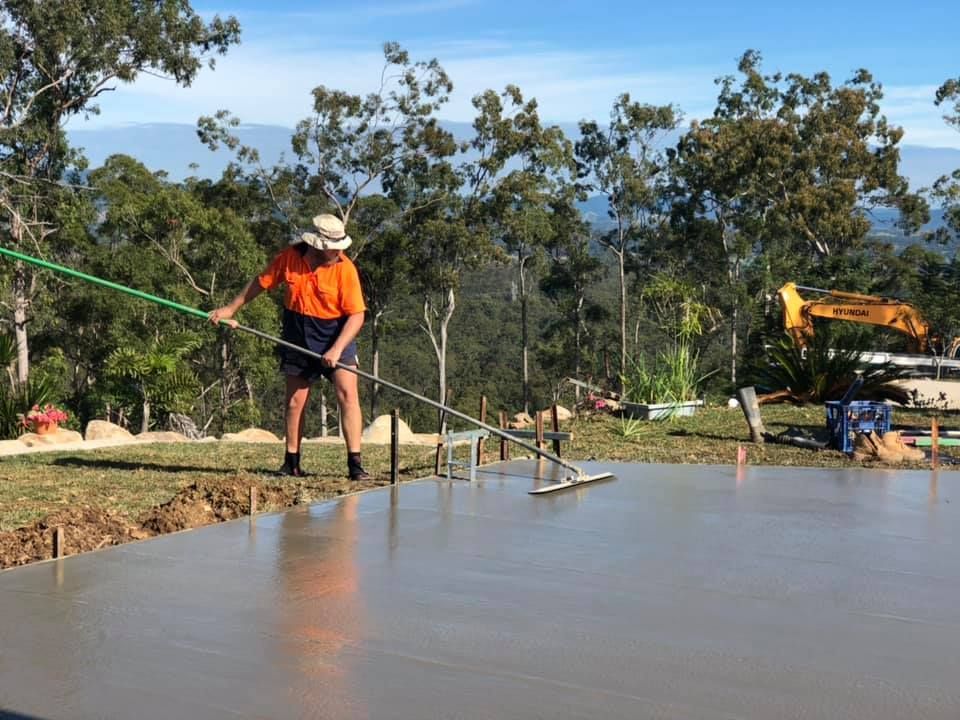 A Man is Standing on a Concrete Surface With a Broom — A2Z Property Services In Kybong, QLD