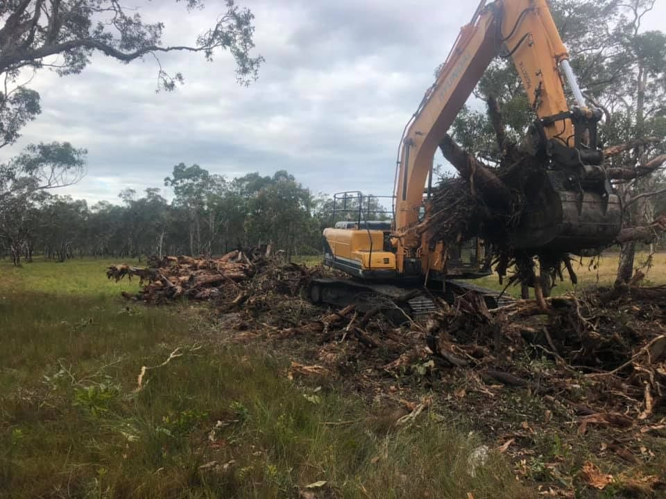 A Yellow Excavator Is Digging A Hole In The Dirt — A2Z Property Services In Cooroy, QLD
