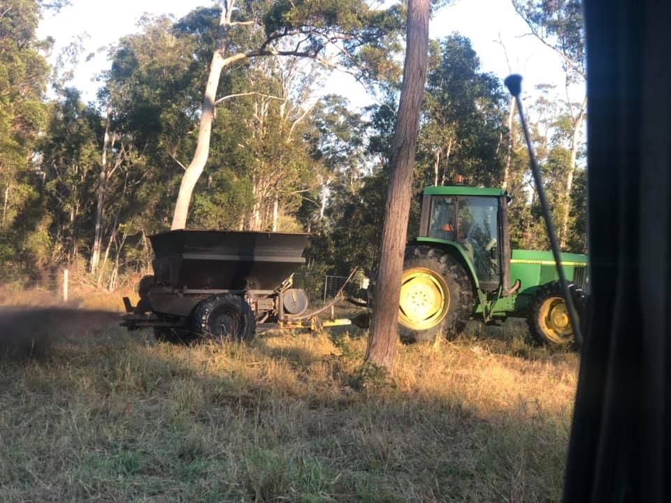 A Green Tractor Is Parked In A Field With Trees In The Background — A2Z Property Services In Kybong, QLD