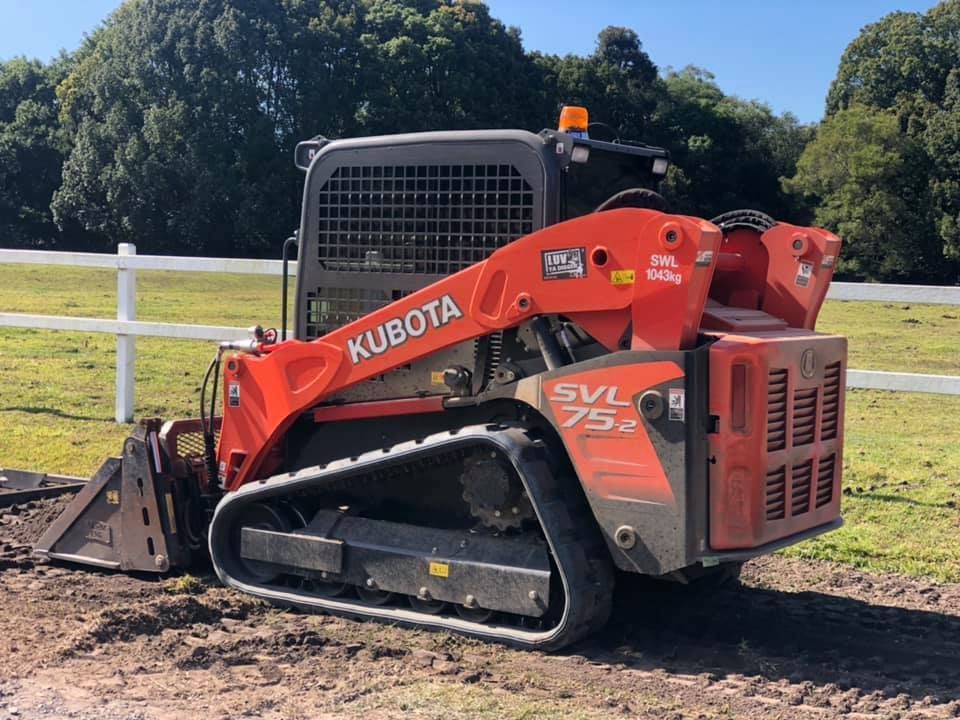 A Red and Black Kubota Skid Steer is Parked in a Dirt Field — A2Z Property Services In Kybong, QLD