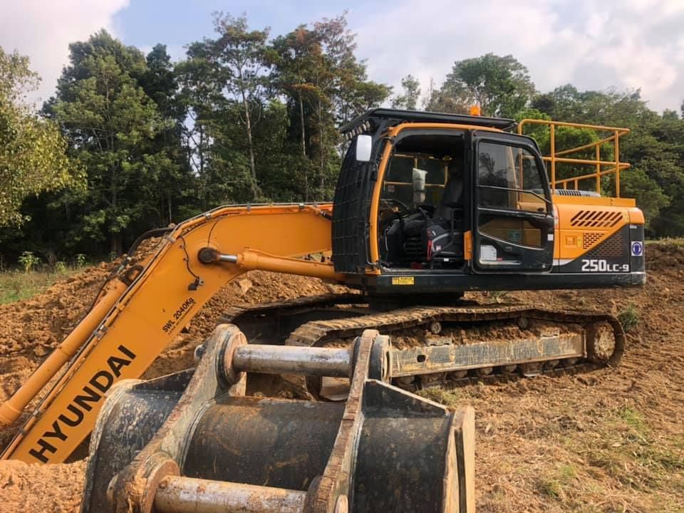 A Yellow and Black Hyundai Excavator is Parked in a Dirt Field — A2Z Property Services In Kybong, QLD