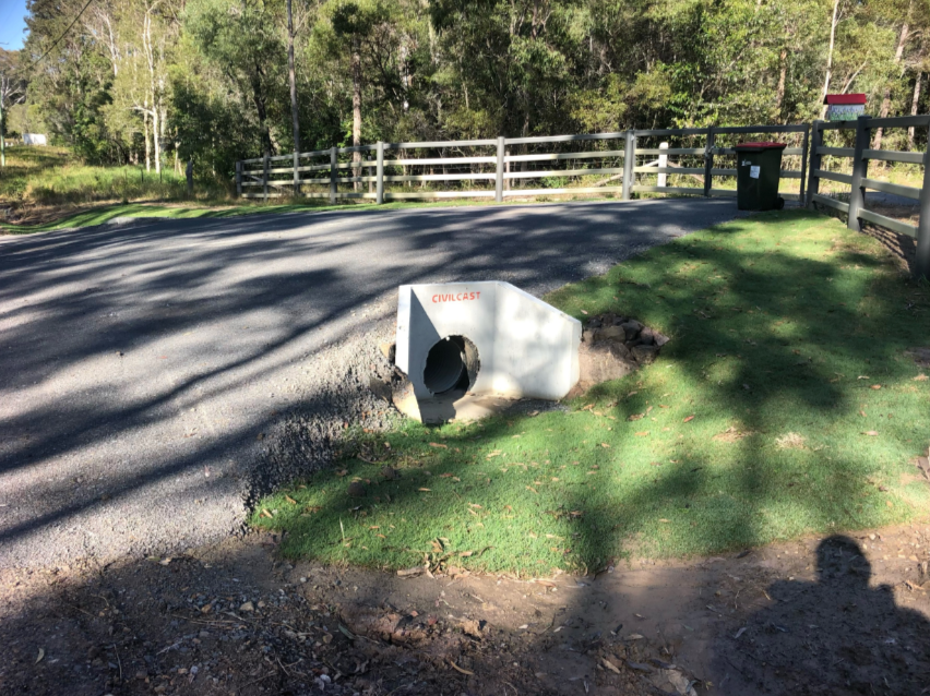 A Concrete Pipe Is Sitting In The Grass Next To A Road — A2Z Property Services In Gympie, QLD