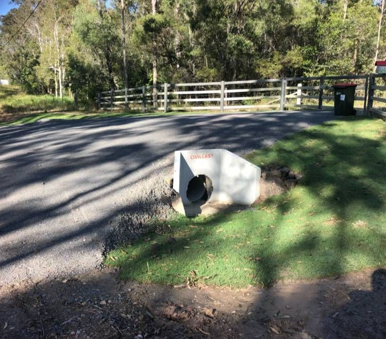 A Concrete Pipe Is Sitting In The Grass Next To A Road — A2Z Property Services In Kilkivan, QLD