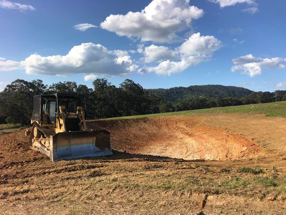 A Bulldozer Excavating a Pit in A Field — A2Z Property Services In Cooroy, QLD