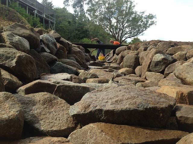 A Person Is Standing On A Bridge Surrounded By Rocks — A2Z Property Services In Kybong, QLD