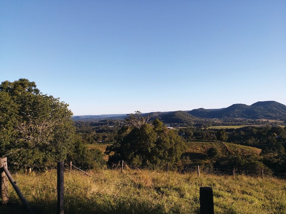 A Fenced In Field With Trees And Mountains In The Background — A2Z Property Services In Eumundi, QLD