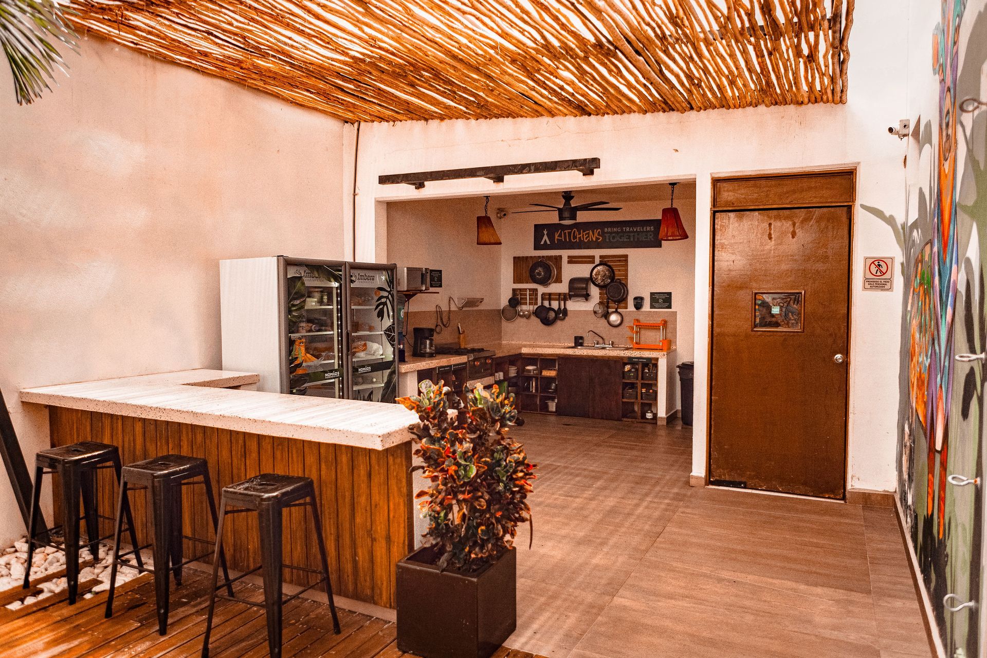 A kitchen with a wooden counter and stools and a refrigerator.