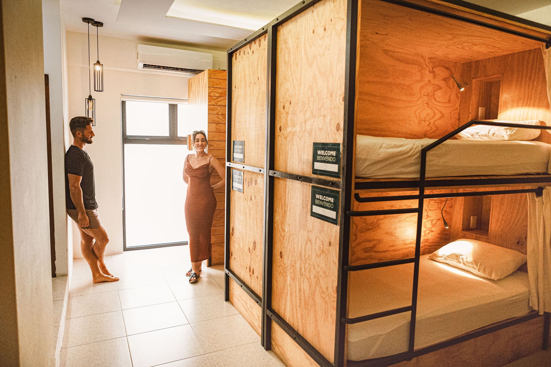 A man and a woman are standing in a room with bunk beds.