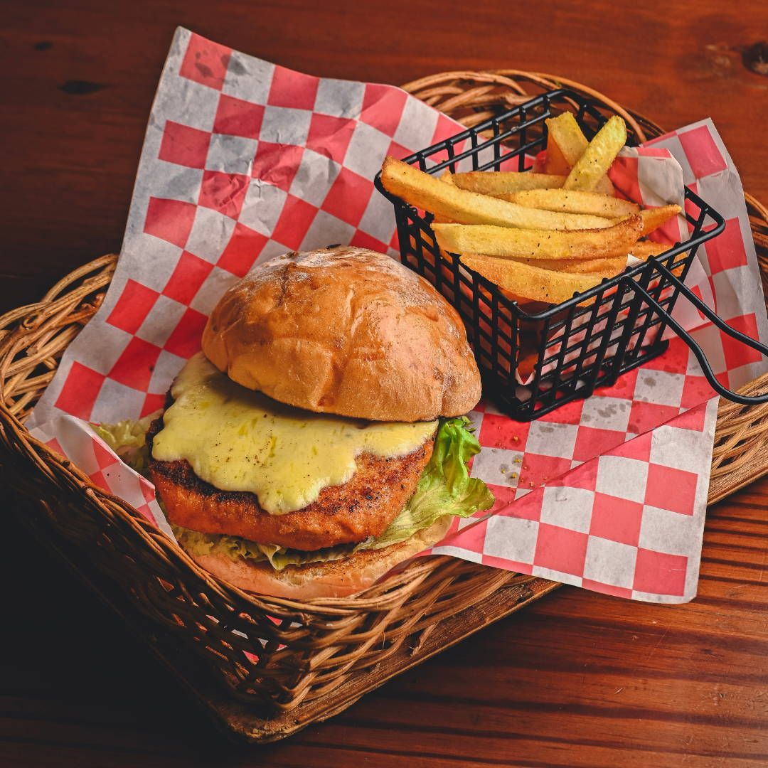 A hamburger and french fries in a basket on a wooden table.