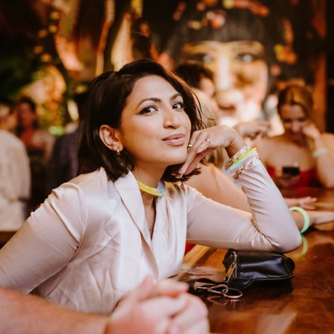 A woman sitting at a table with her hand on her chin