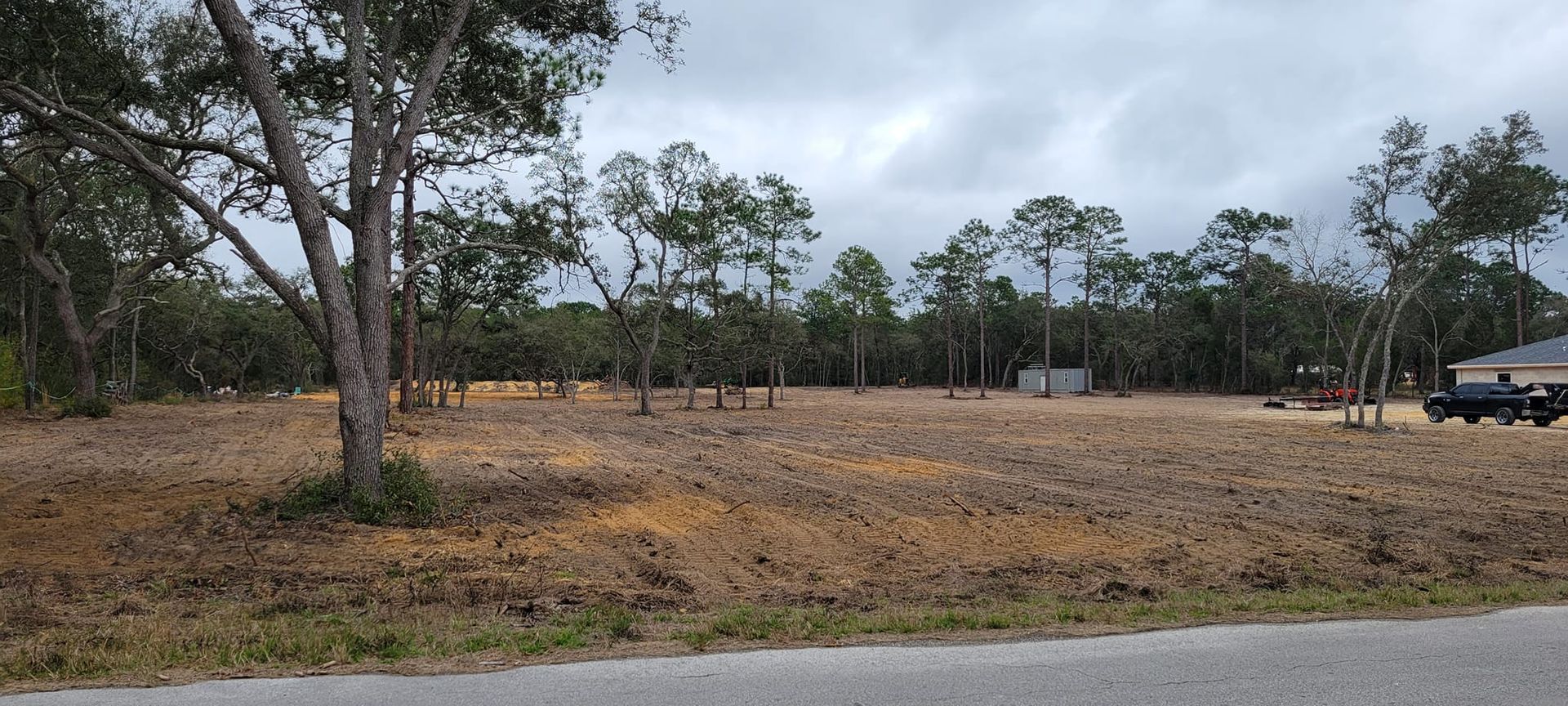 Cleared lot with trees in the background under an overcast sky.
