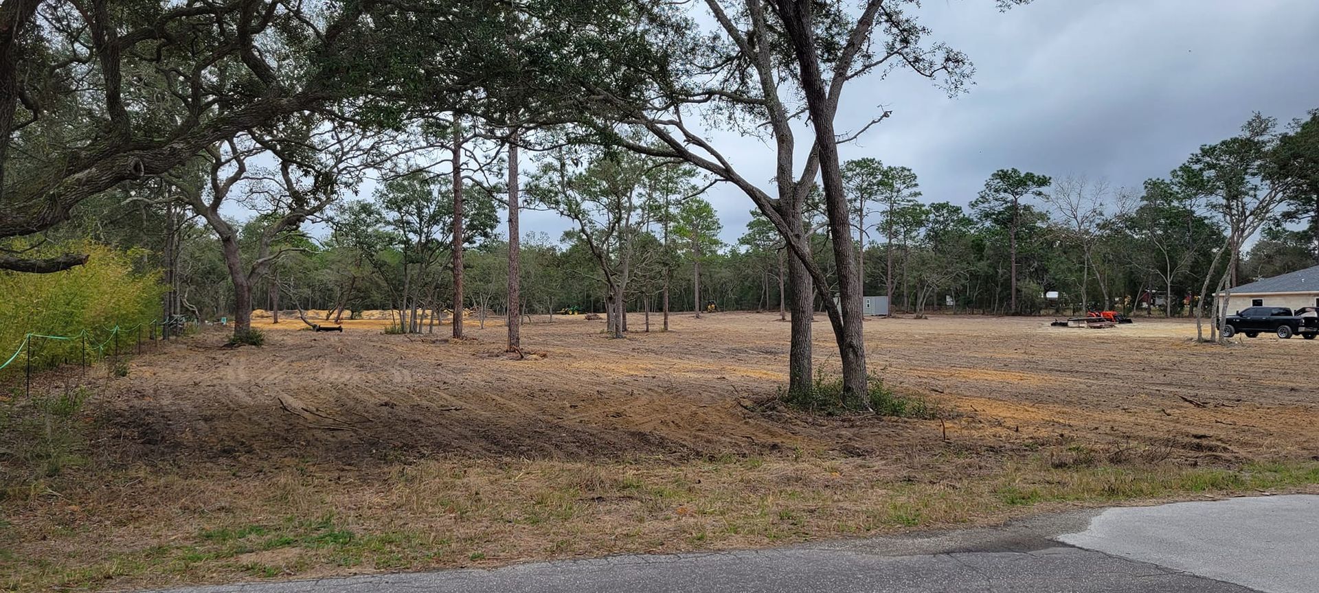 A cleared lot with trees in the background, under a cloudy sky.