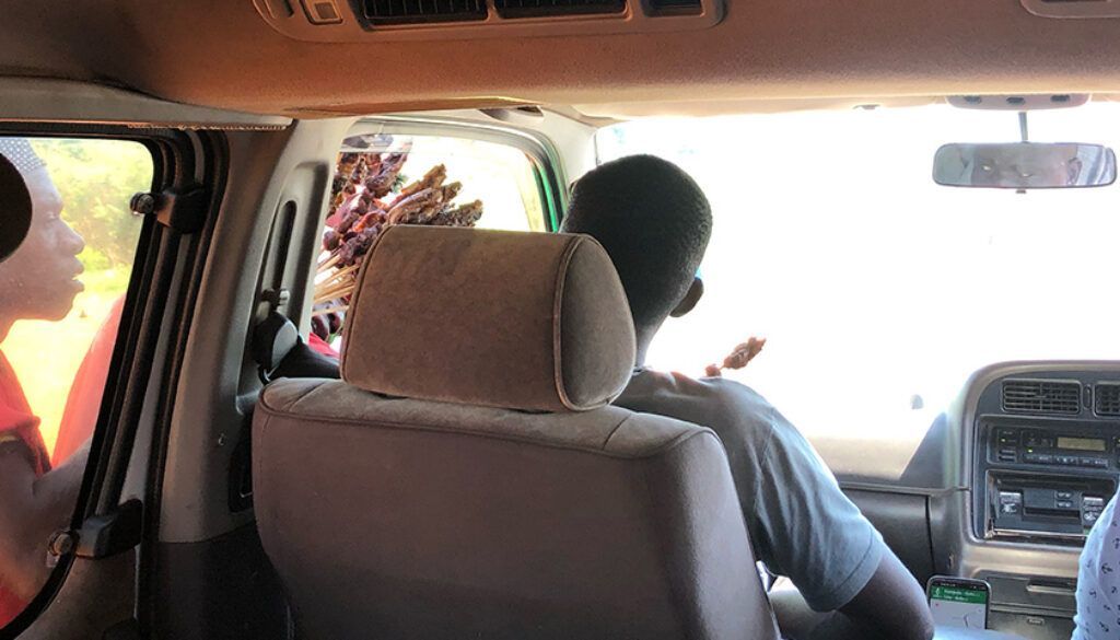 Interior car view: person turns to face the open window as a person leans in from outside.