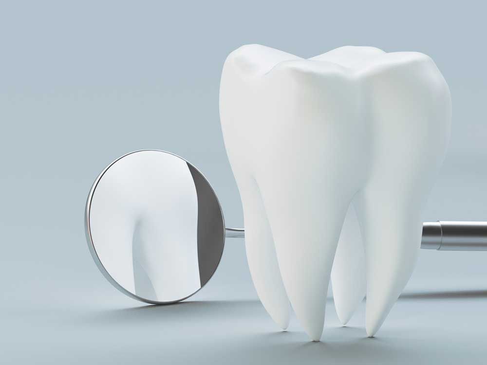 Tooth and dental mirror against a gray background.