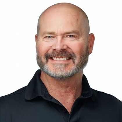 A man is holding a dog in his arms and the dog is wearing a sweater.