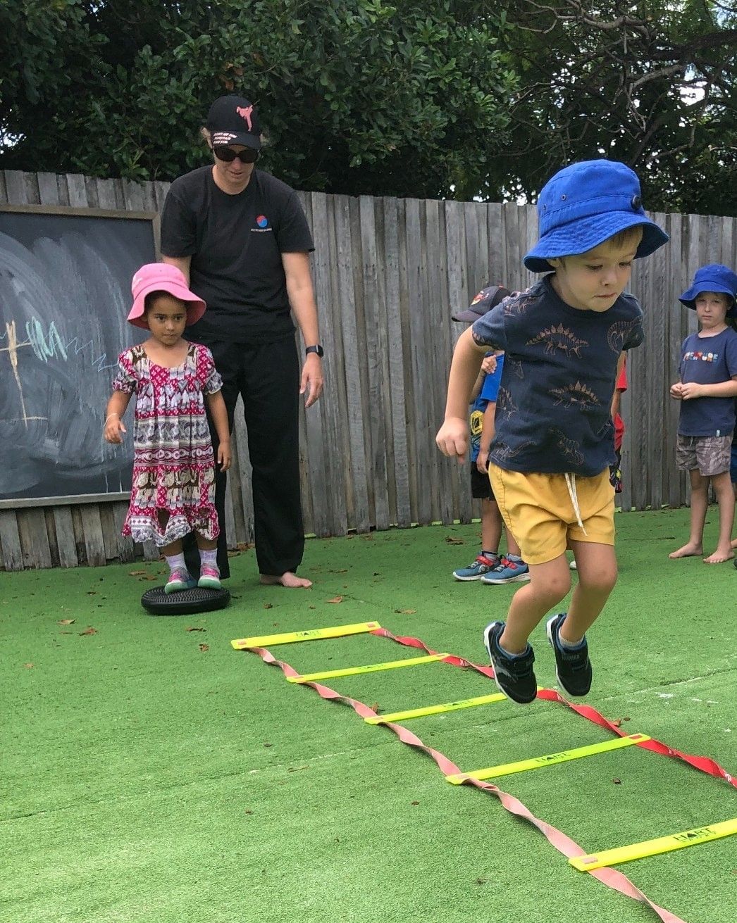 A Young Boy Wearing A Blue Hat Is Climbing A Tree – Bundaberg North, QLD - Cradle to Crayons Education & Care