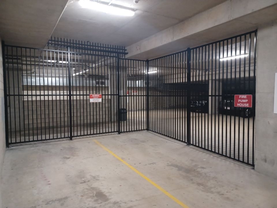 A fenced-off area in a concrete parking garage with two signs reading 