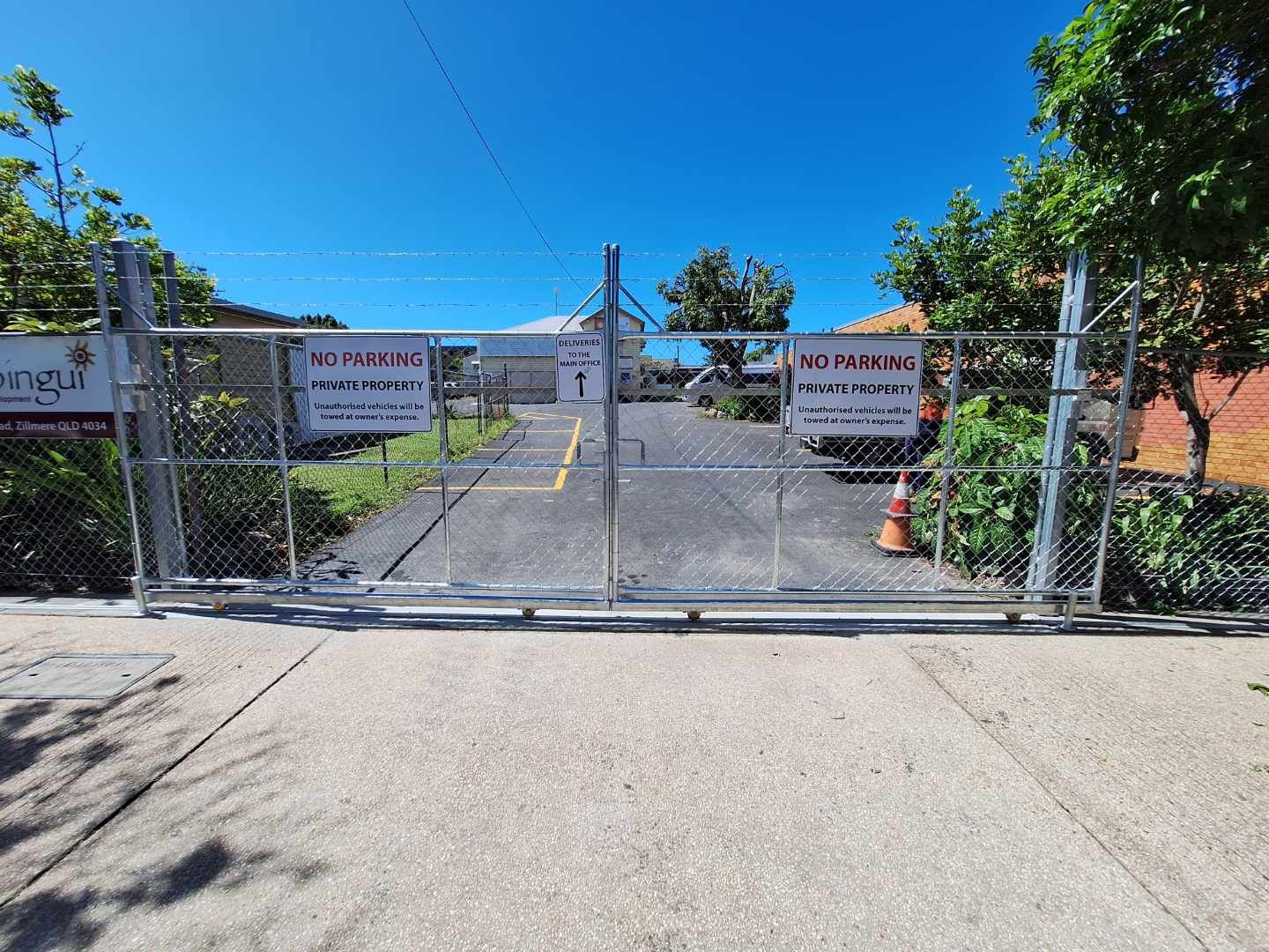 A chain-link fence gate closes off a paved driveway with 
