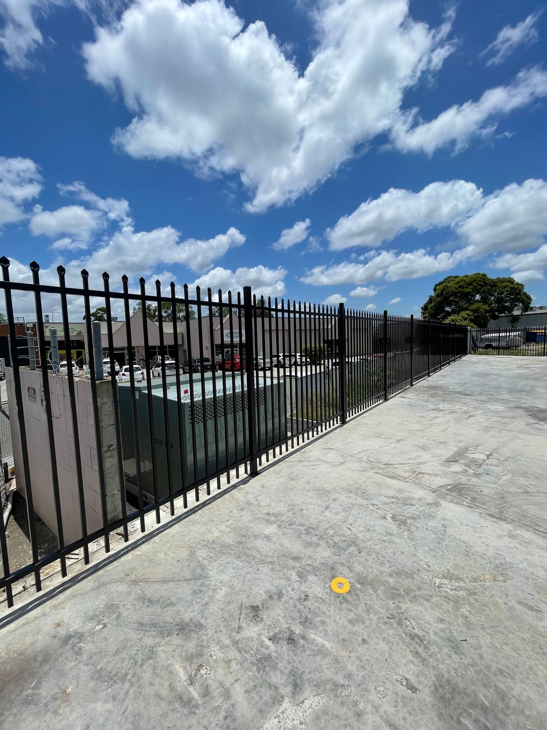 A modular, silver metal chain-link security enclosure or storage cage with two hinged doors, standing against a white wall.