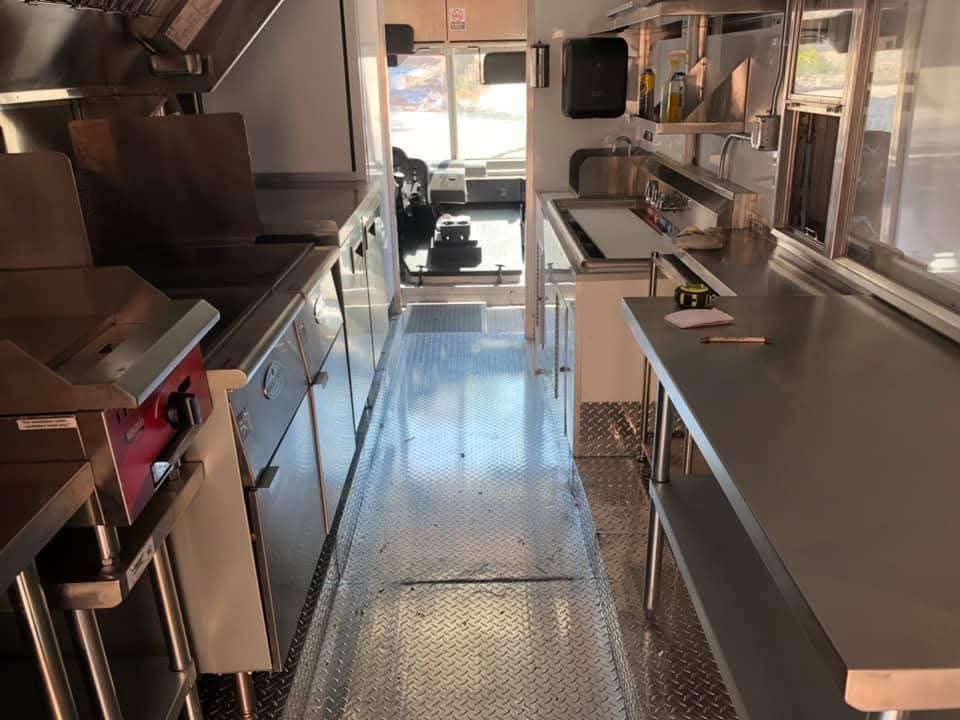 Interior of a food truck. Stainless steel equipment and countertops line the walls.