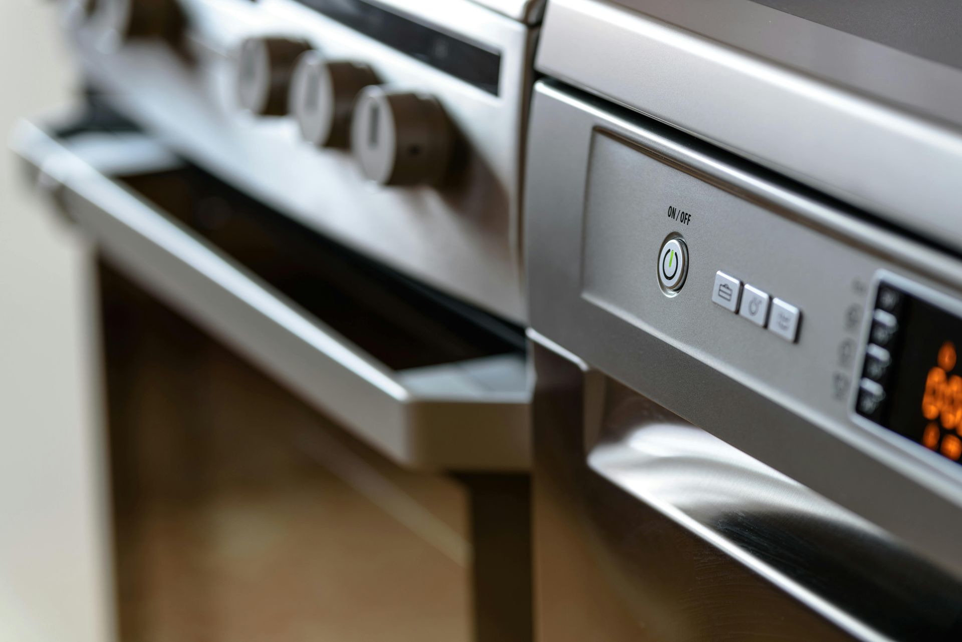 Close-up of a silver oven and stove top with control knobs and a digital display.