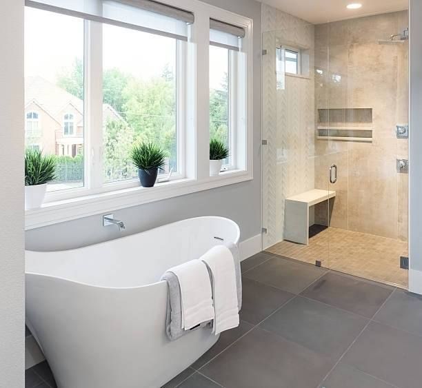 Modern bathroom with freestanding tub, large window, and walk-in shower with bench.