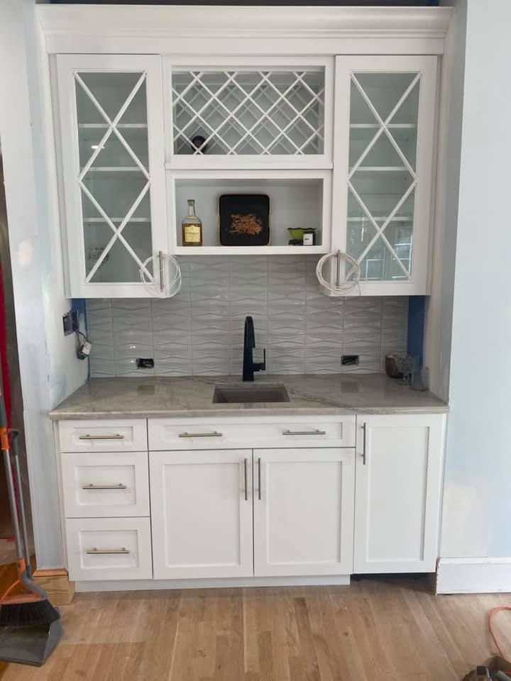 White built-in bar with cabinets, sink, backsplash, and wine rack.