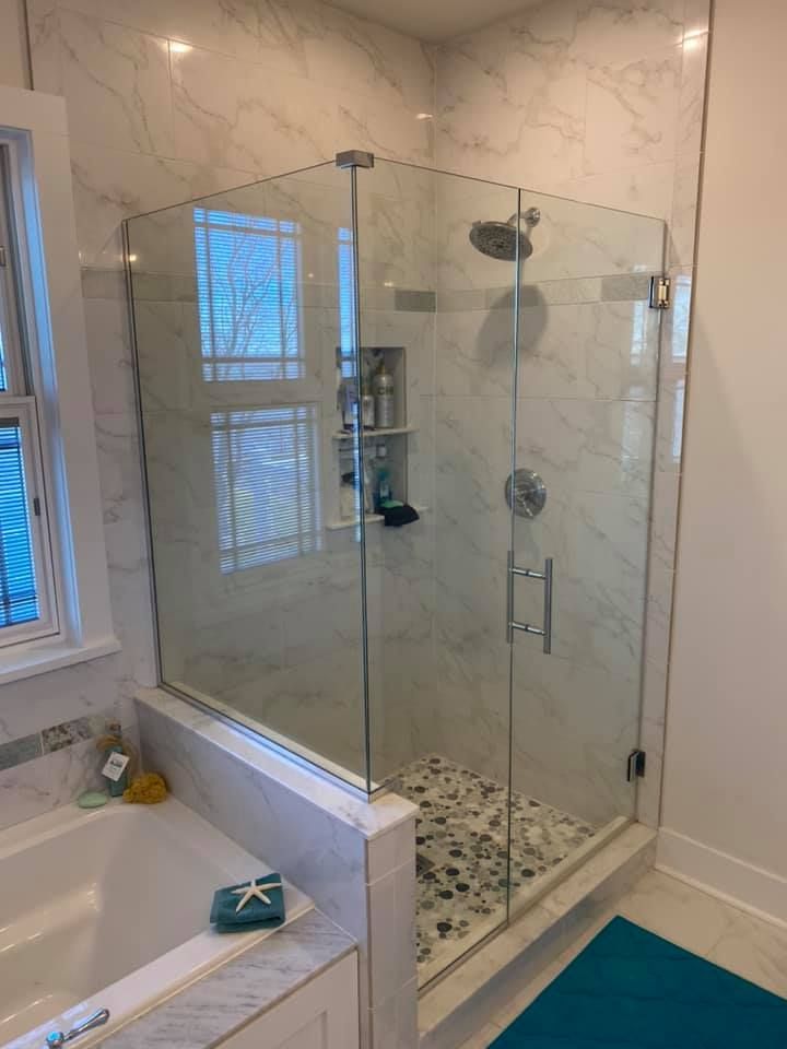 Glass shower enclosure with marble tile walls and pebble floor.