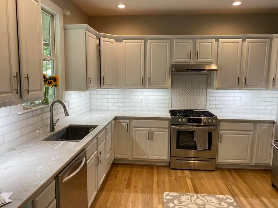 Kitchen with white cabinets, subway tile backsplash, stainless steel appliances, and wooden floor.