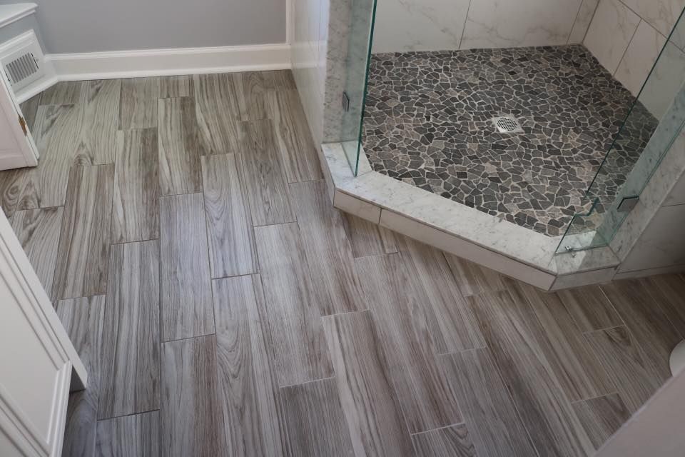 Bathroom with wood-look tile flooring and a pebble-tiled shower.