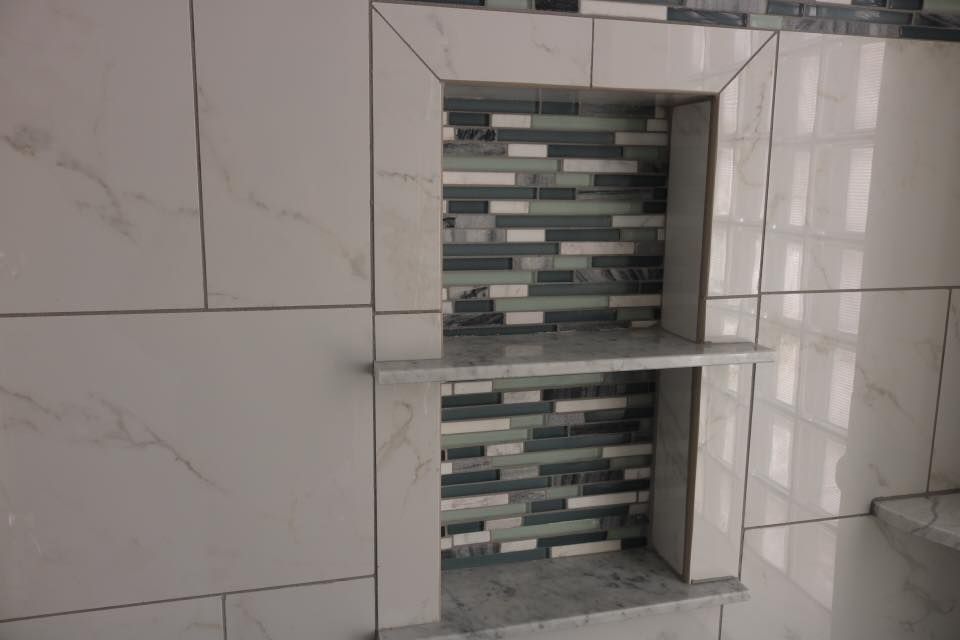 Recessed shower shelf with marble-look tile and mosaic tile back, with a shelf.