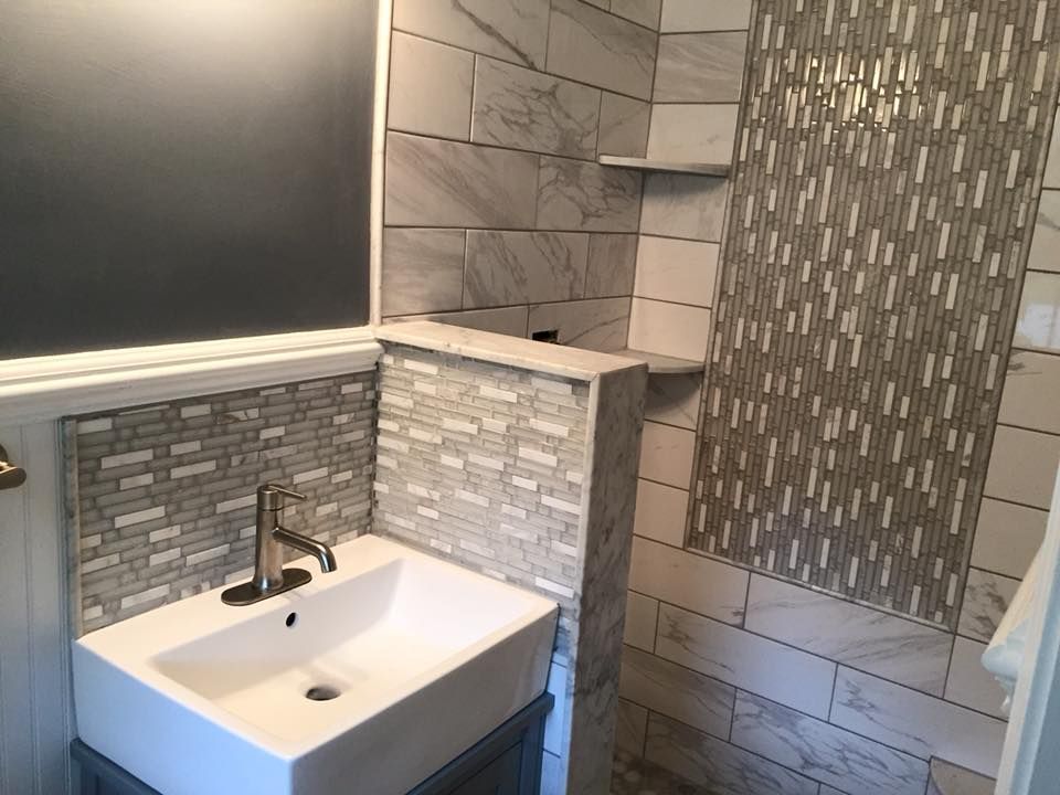 Bathroom with gray and white tile, a square sink, and a small built-in shelf.