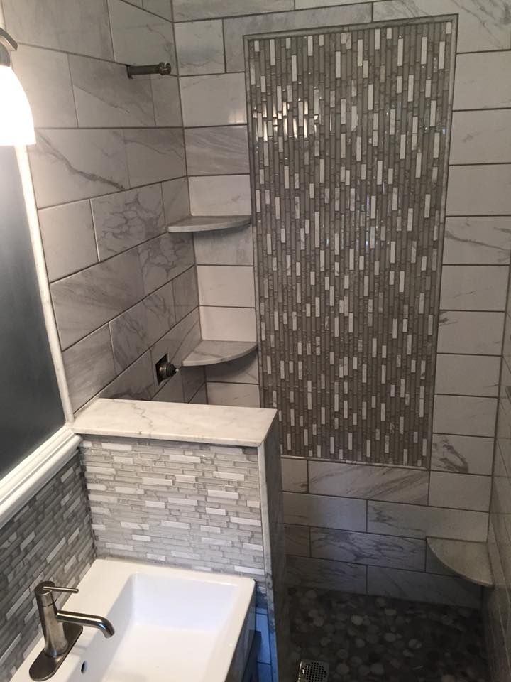 Bathroom with tiled walls, a shower, sink, and decorative mosaic accents.