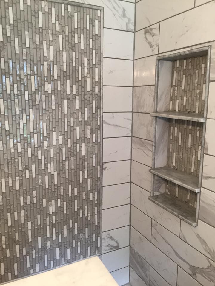 Shower with marble-look tile, a mosaic accent wall, and built-in shelves.