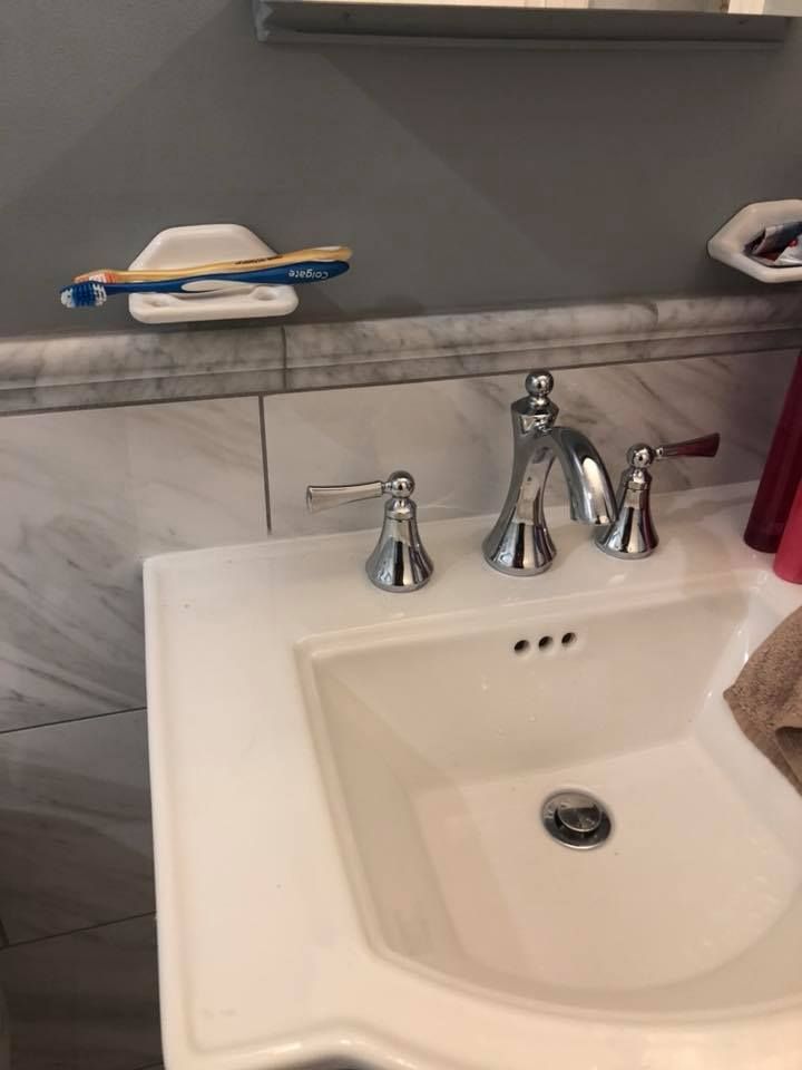 Bathroom sink with chrome faucet, white countertop, and toothbrush holder.