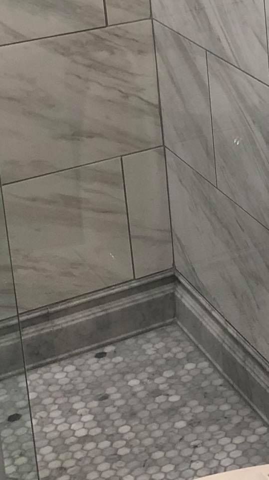 Gray and white tiled shower with a hexagon tile floor.