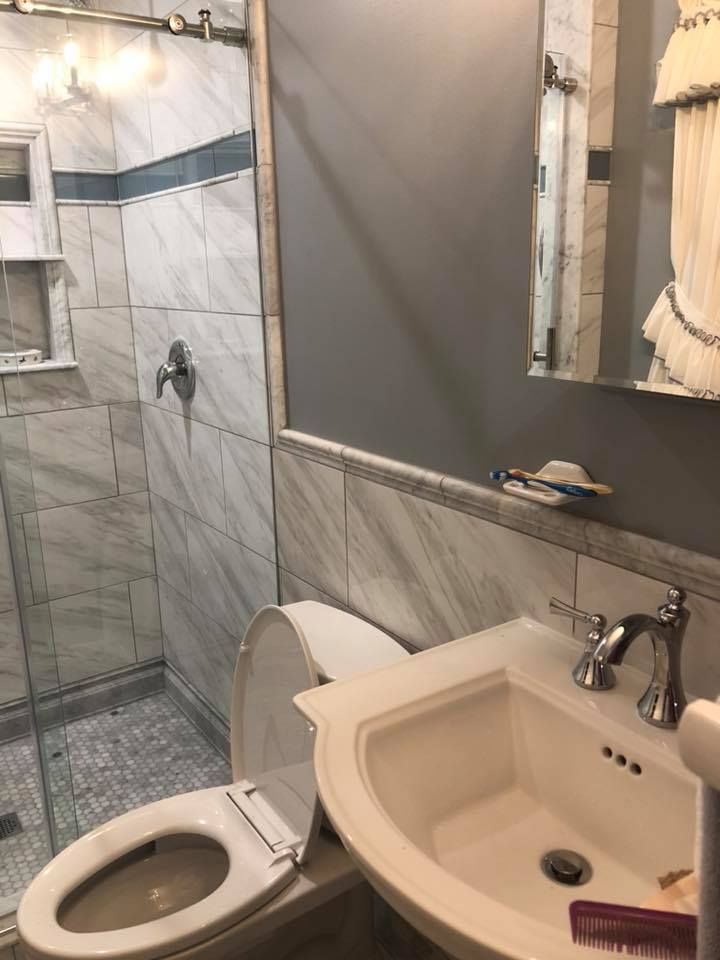 Bathroom with marble tile shower, gray walls, white sink and toilet.