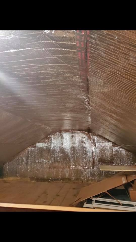 Insulation material on an attic ceiling, appearing to be sealed with silver tape.