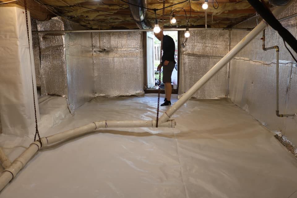 Man standing in a clean, white-lined crawlspace with pipes.