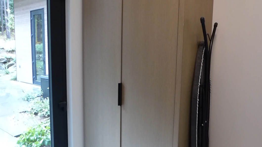 A room with a closet and a window with a coat rack hanging on the wall.