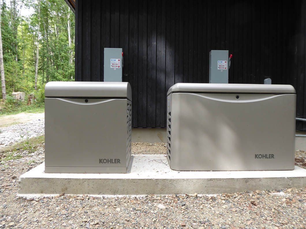 Two kohler generators are sitting next to each other in front of a building.