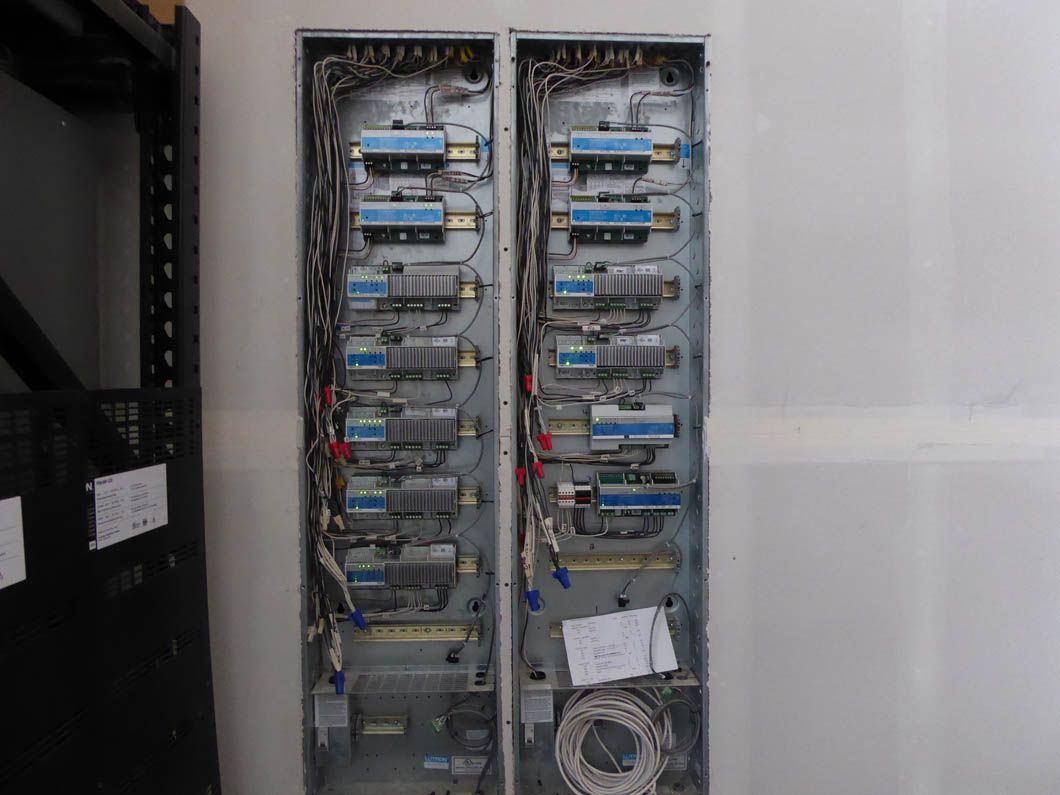 Two electrical boxes are sitting next to each other on a white wall.