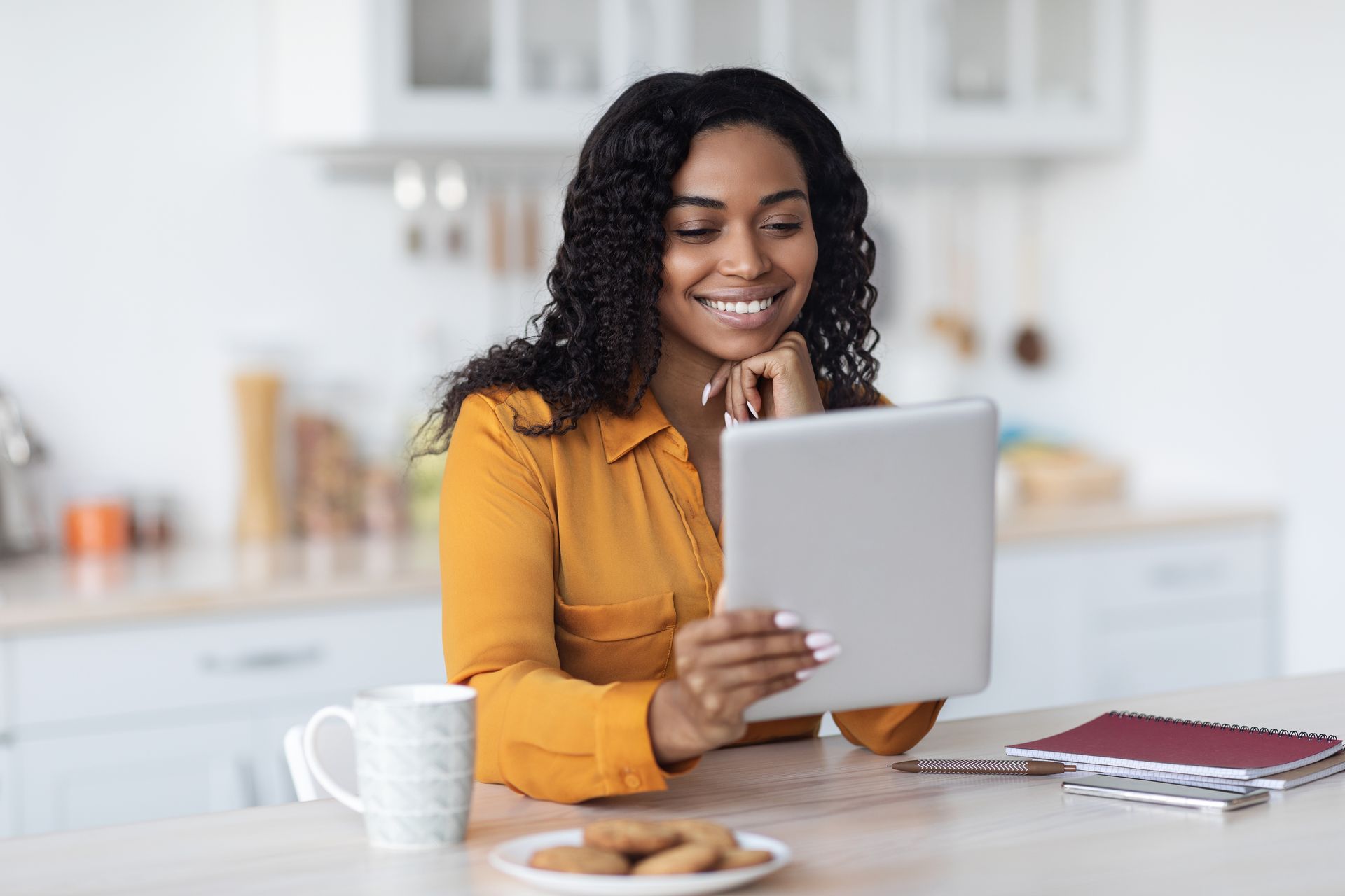 A woman is sitting at a table using a tablet computer.