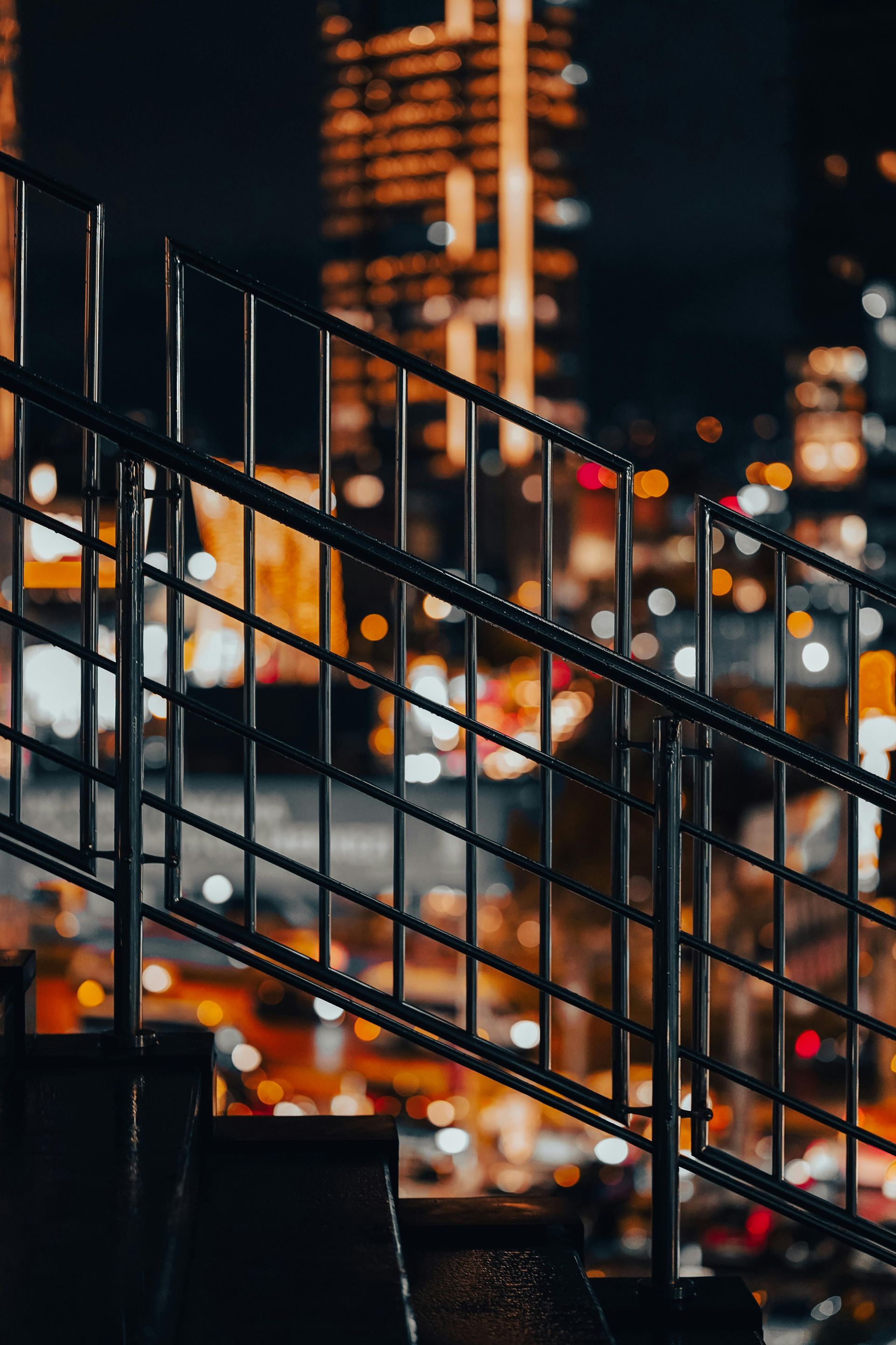 Metal staircase railing in front of blurred city lights at night
