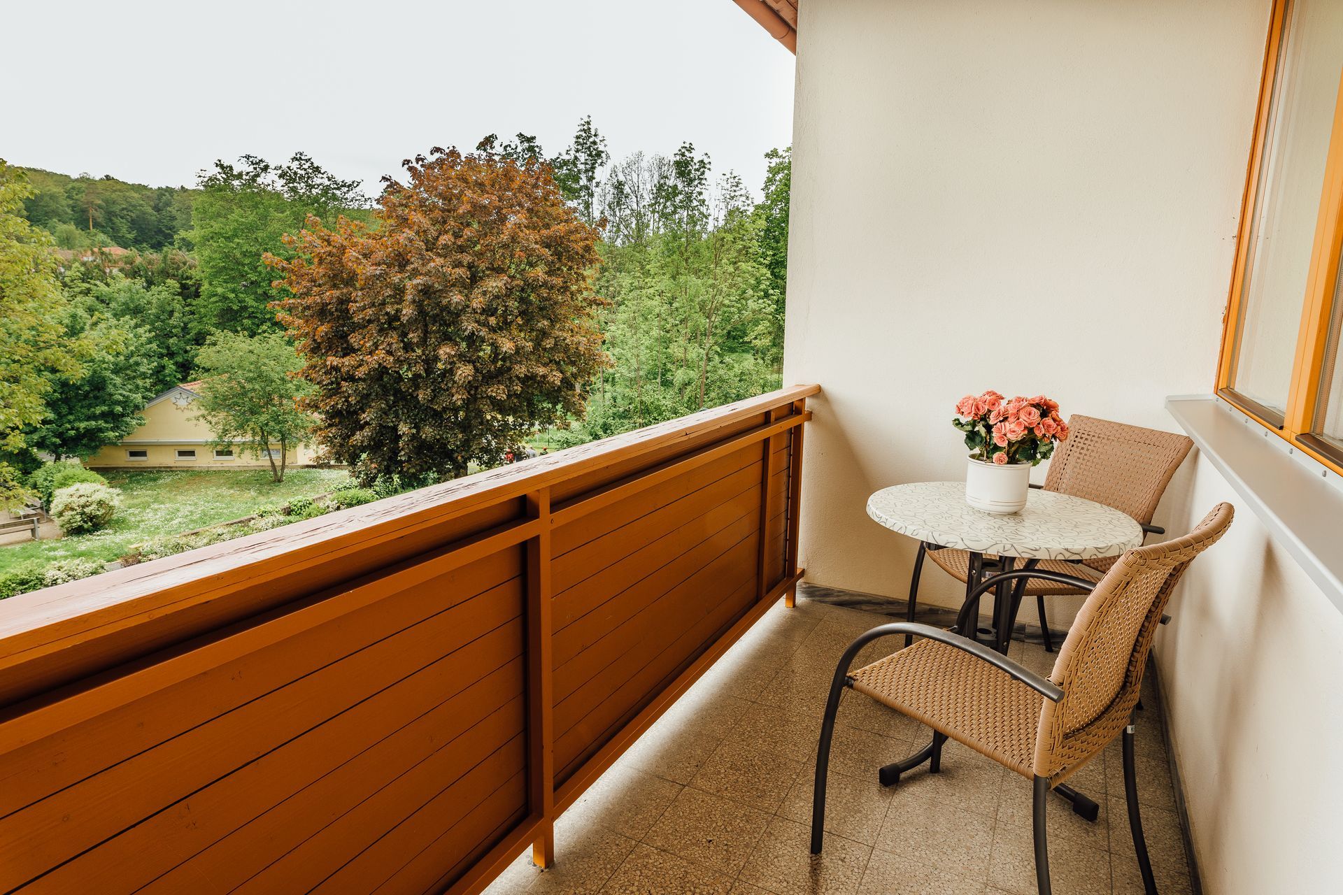 Balkon mit Tisch und Stühlen mit Blick auf Bäume und ein Gebäude.