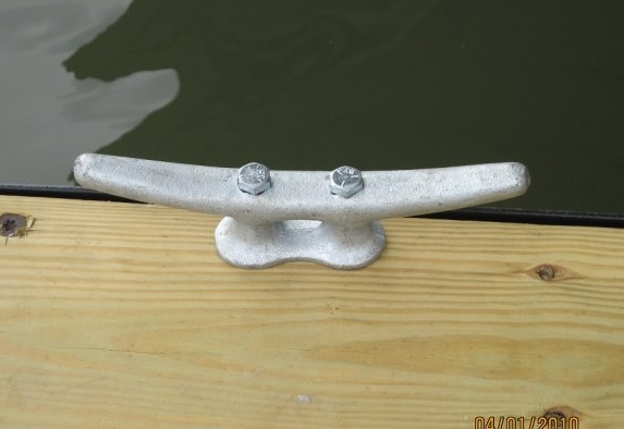 A close up of a boat cleat on a wooden dock