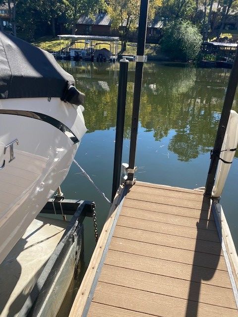 A boat is docked at a dock with a reflection of trees in the water