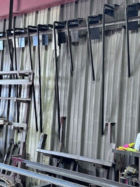 A bunch of chairs are hanging on a wall in a factory.