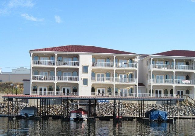 A large white building with a red roof is next to a body of water