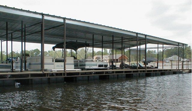 A boat is docked under a covered dock on a lake